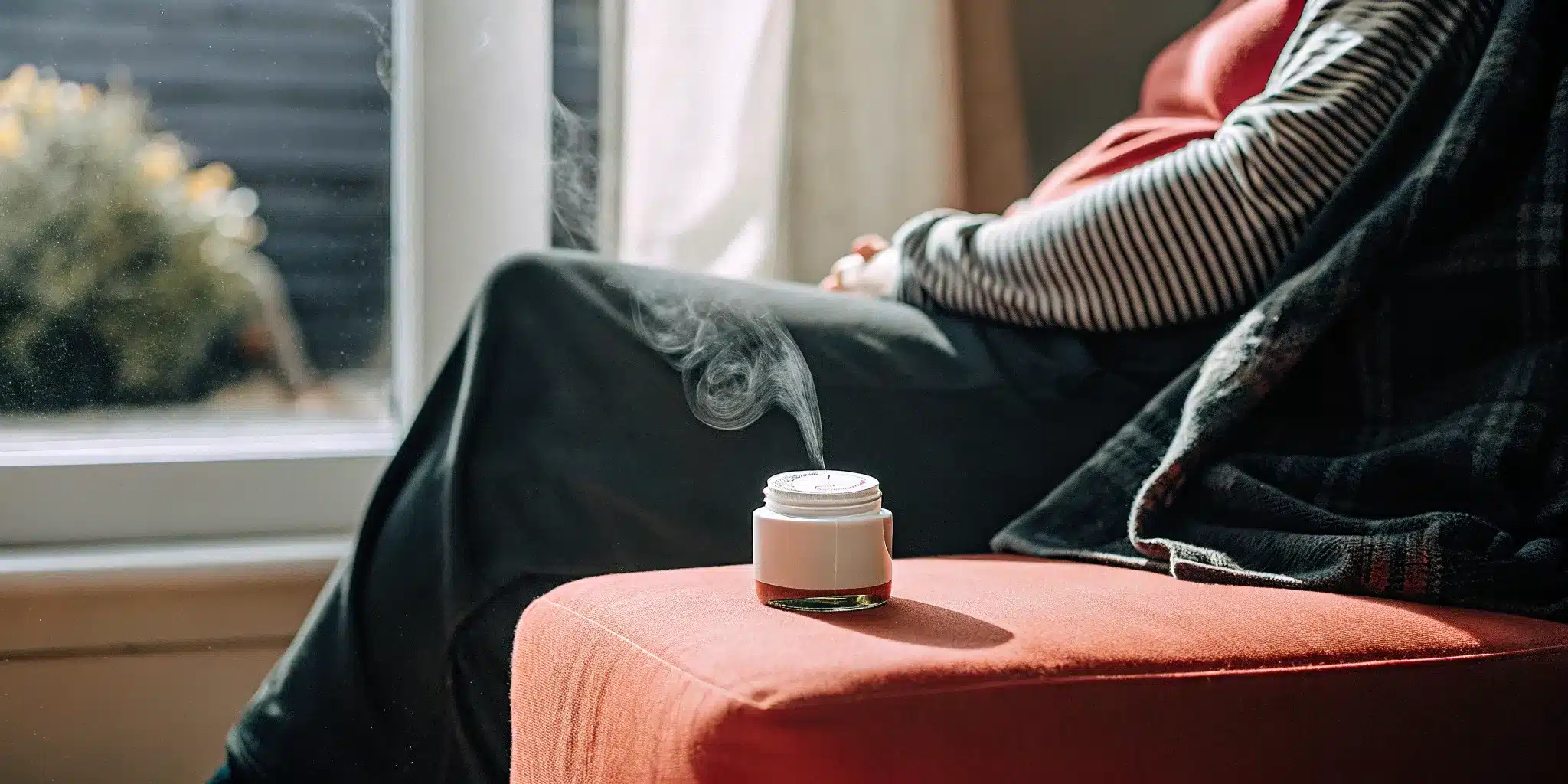 A person relaxing at home with a jar of camphor and menthol rub releasing soothing vapor.